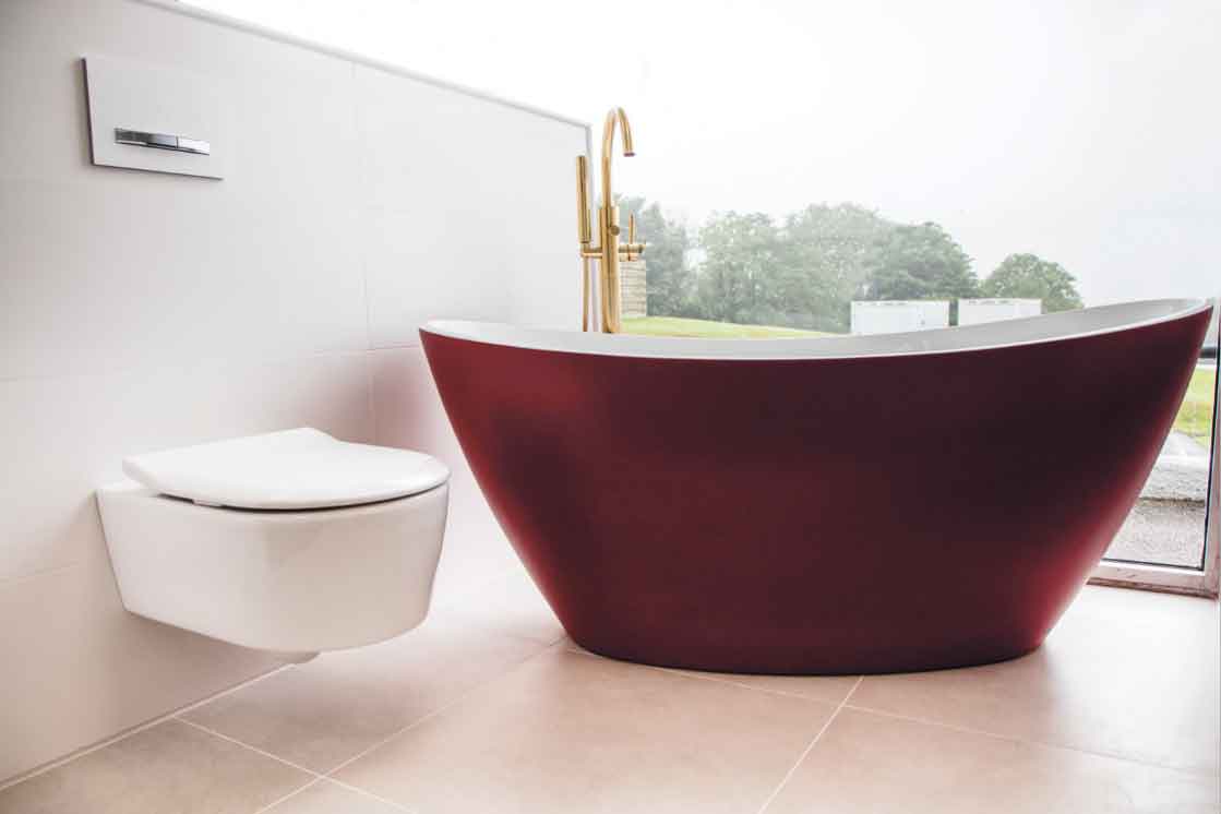 Red freestanding bath with gold taps. Available from Westcountry Tile and Bathroom