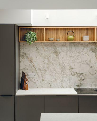 Close up of the grey kitchen units and white worktop. Wooden shelves add warmth