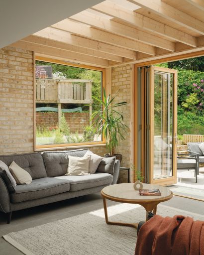 View of sofa beneath a large window with bifold doors opening out onto the garden