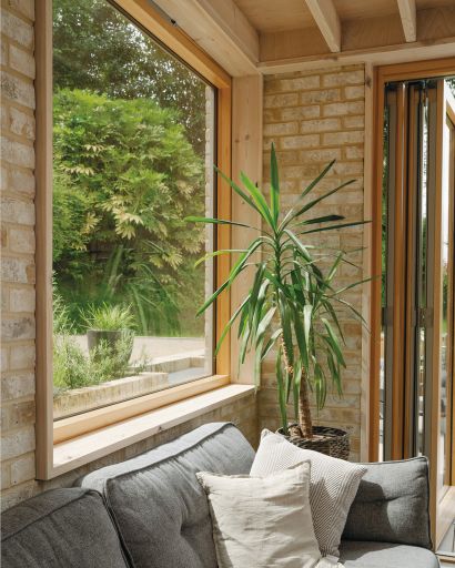 Close-up of a large window above a grey sofa. Looks out to the garden beyond