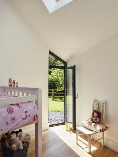 The children’s bedrooms each have a glazed door connected to the outside behind a projection of the outer wall. This brings in plenty of light, and allows the children to nip in and out of the garden