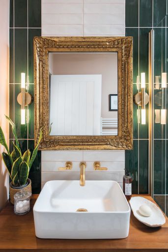 Kohtalo. Bathroom. Counter-top sink with gold taps. Gold framed mirror. Green bathroom tiles
